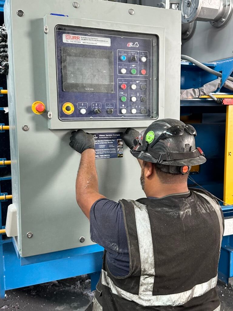 HSC technician placing sticker after preventative maintenance on a single-ram auto-tie baler