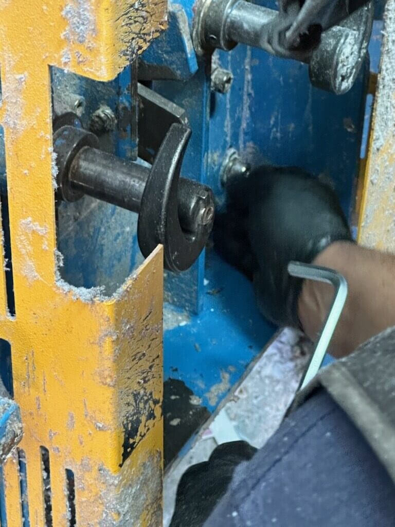 HSC technician performing preventative maintenance on a single-ram open-end auto-tie baler